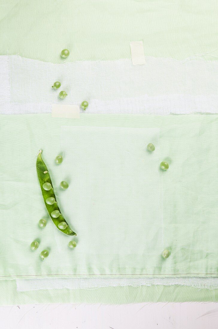 Frische Erbsen auf hellgrünem Tuch
