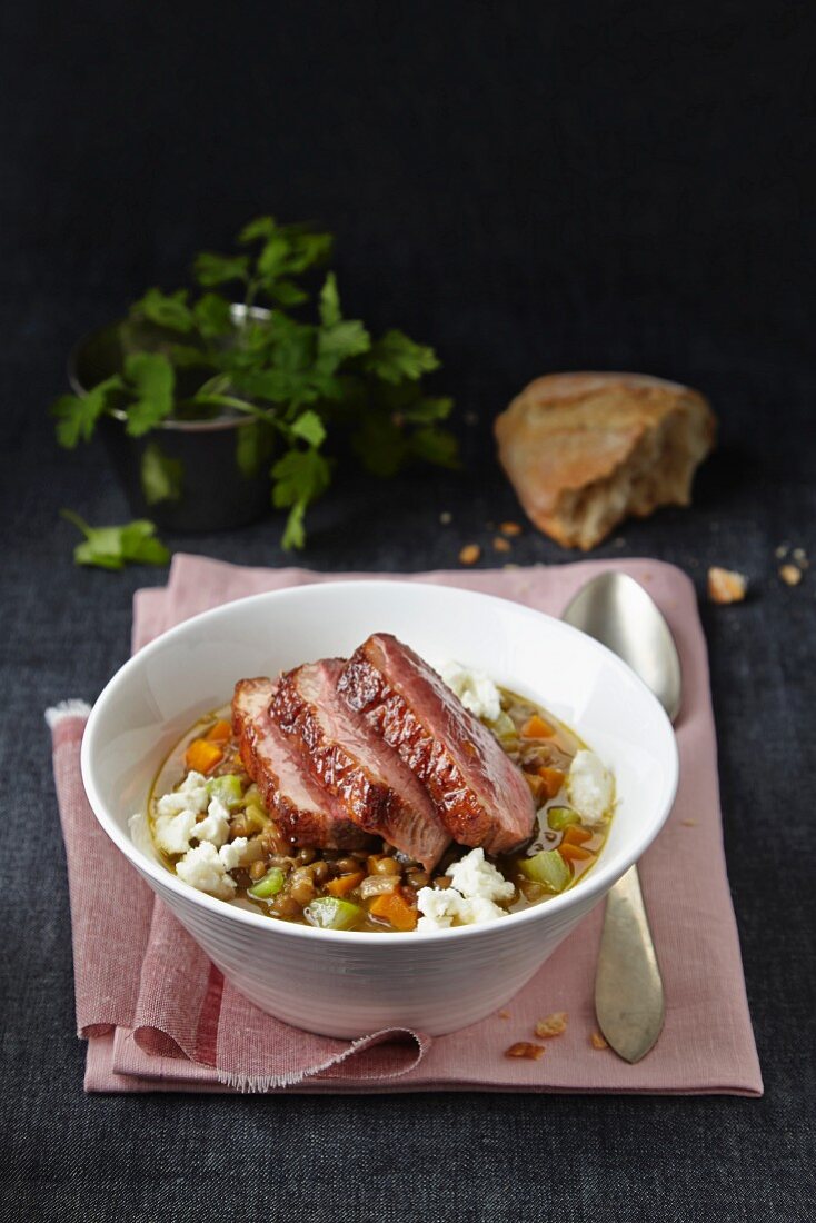 Lentil stew with carrots, celery, feta cheese and duck breast