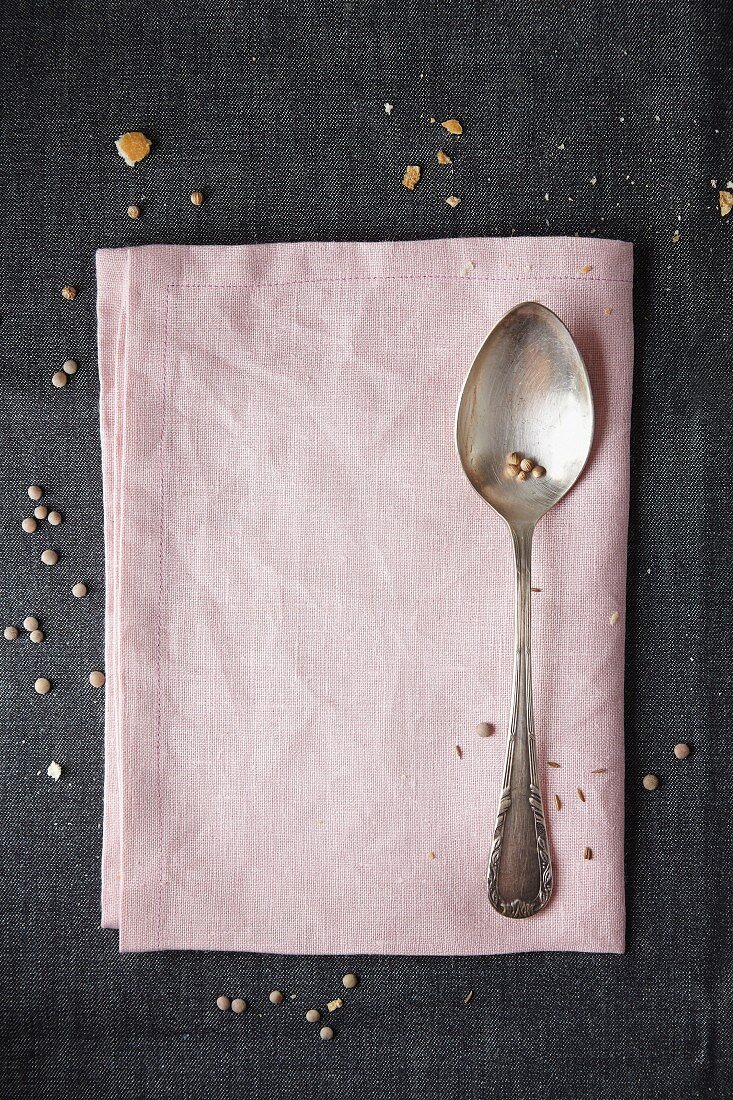 Lentils sprinkled around a fabric napkin and a spoon