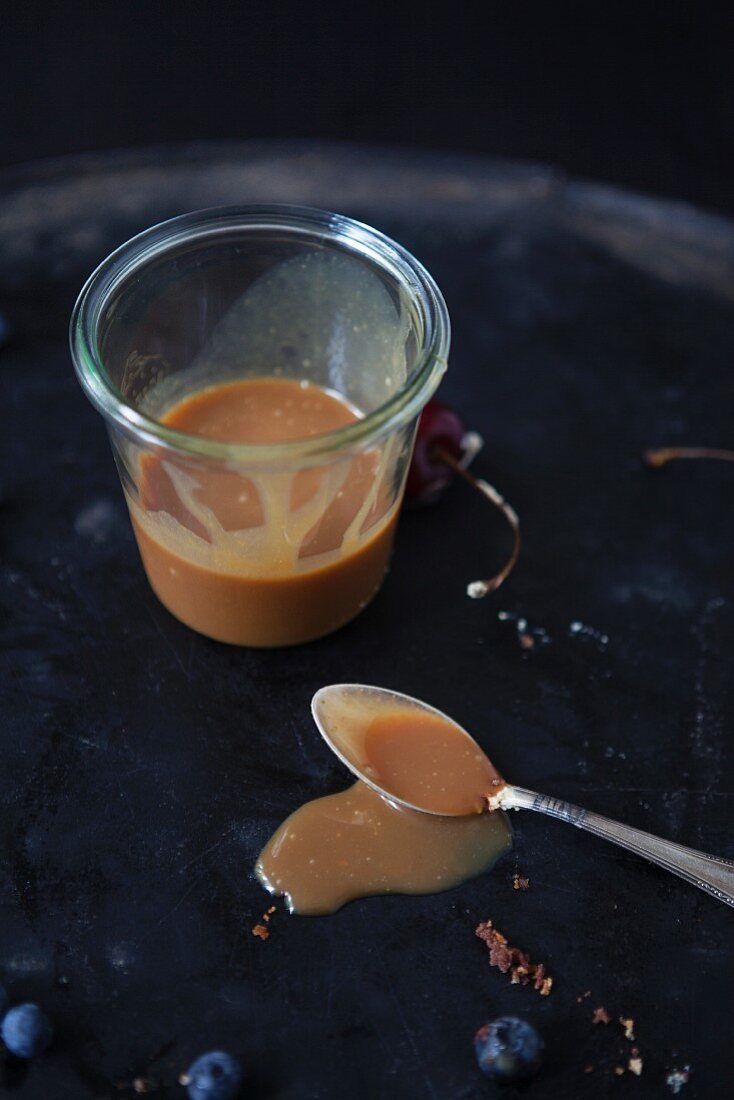Caramel sauce in a glass and on a spoon