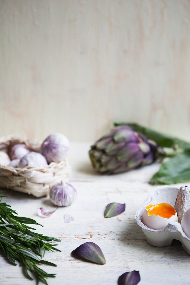 An open soft-boiled egg with field garlic, artichokes and a sprig of rosemary