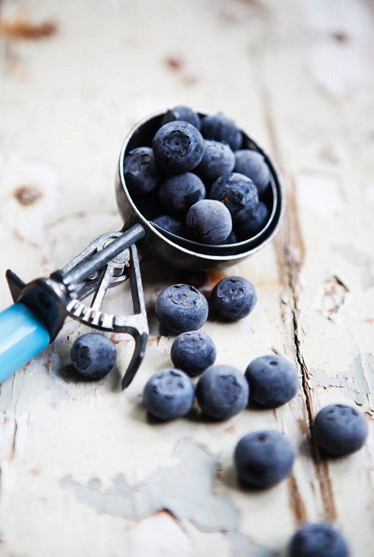 Blueberries in an ice cream scoop on a rustic wooden surface