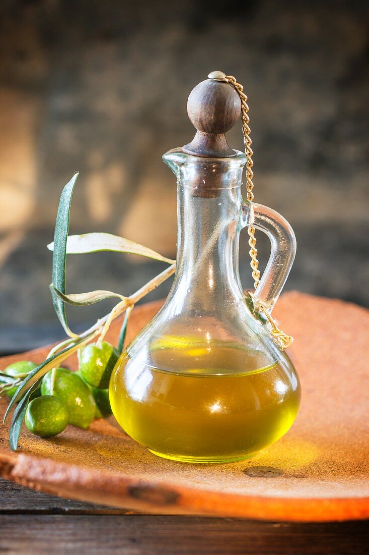 Eine Karaffe Olivenöl und Zweig mit grünen Oliven
