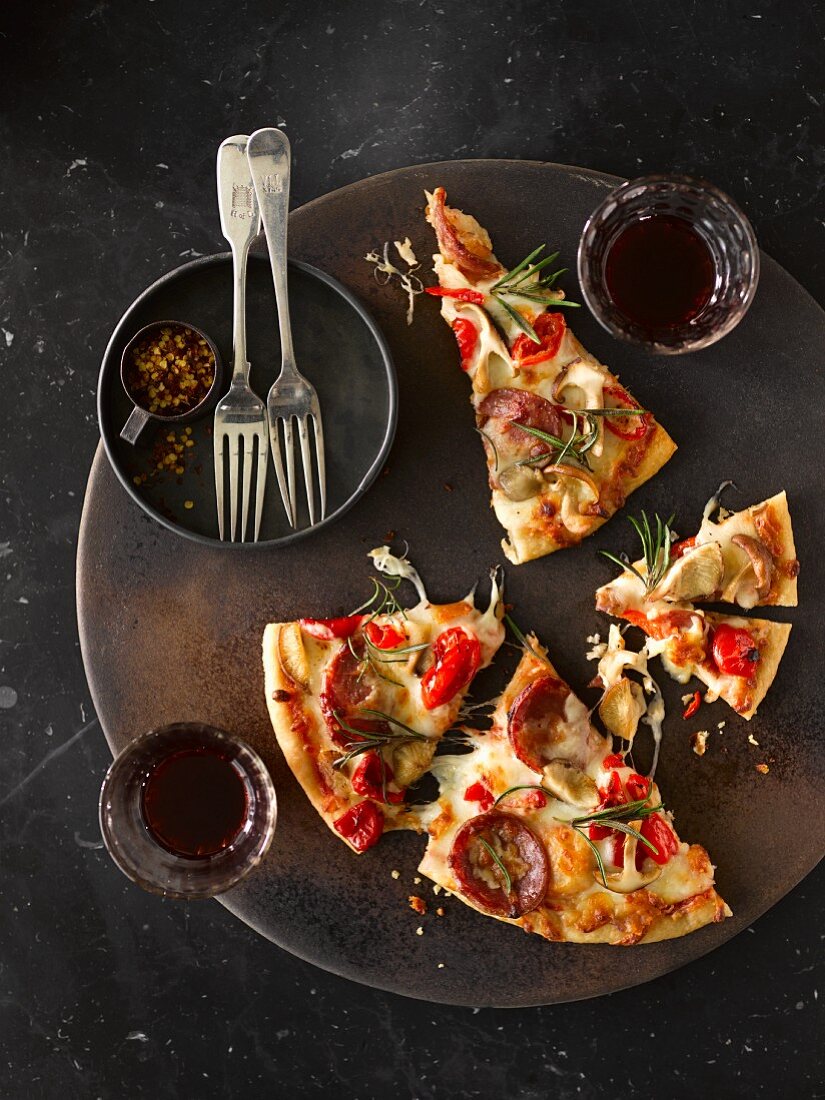 Pizza slices with peperoni, mushroom and pepper served with red wine