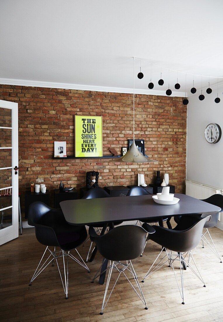 Unrendered brick wall in dining area with wooden floor and designer furniture