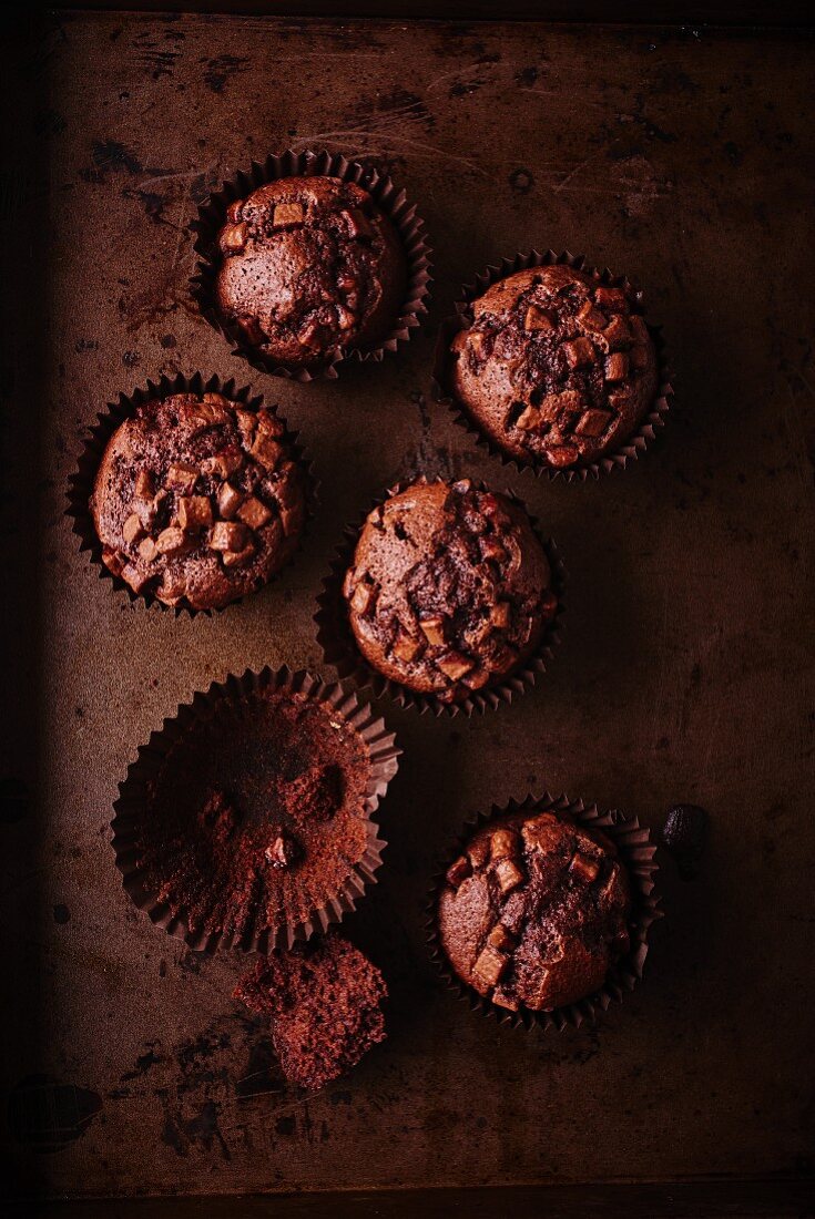 Dunkle Schokomuffins, ein leeres Papierförmchen mit Muffinrest