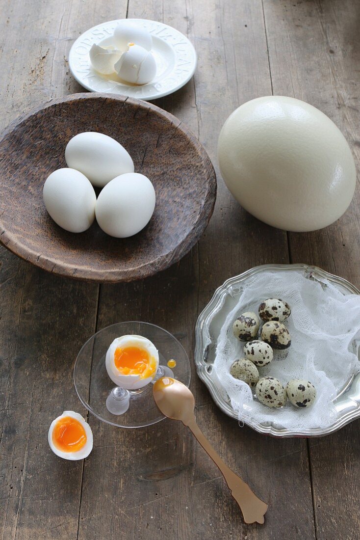 Weichgekochtes aufgeschlagenes Hühnerei mit Eierbecher und Eierlöffel auf Holztisch