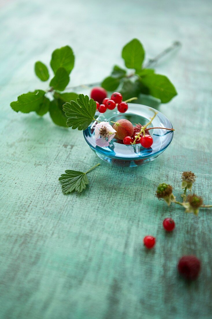 Verschiedene Beeren mit Blättern in Glasschale