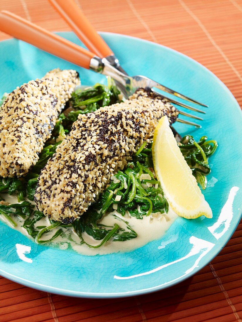 Steamed salmon fillets with a sesame and poppy seed coating on a bed of spinach