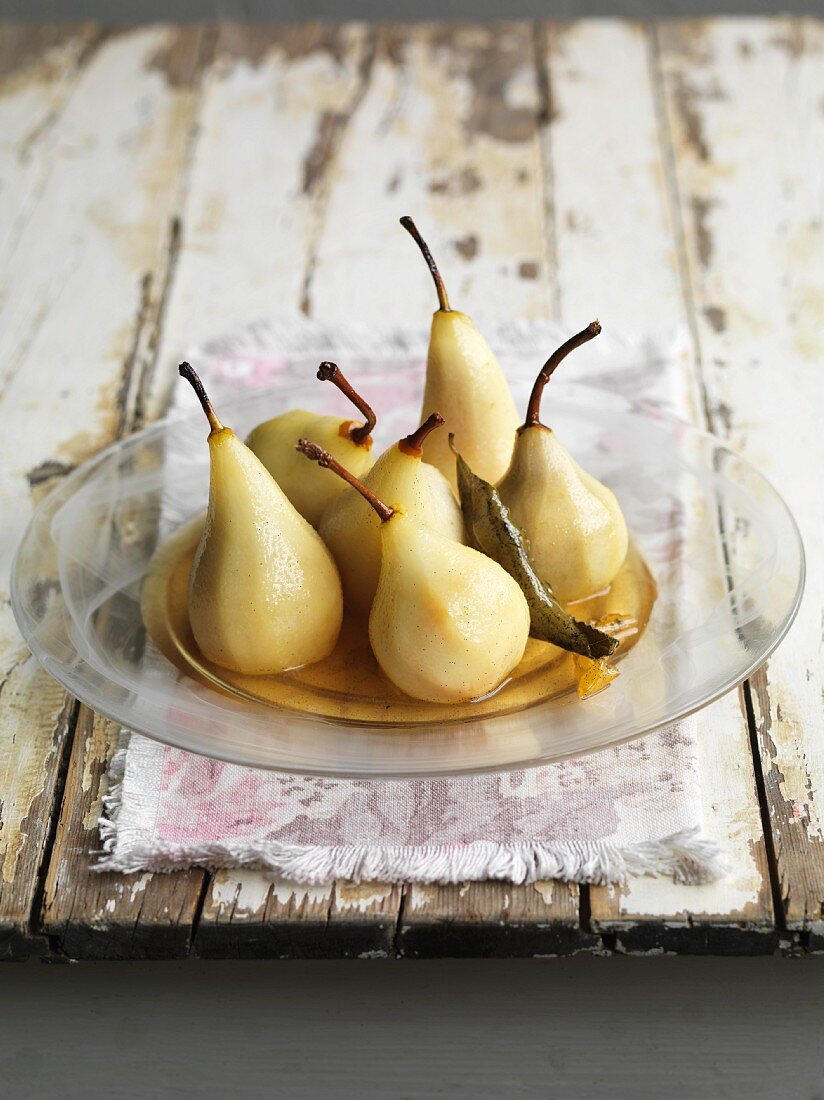 Poached vanilla pears in syrup on a glass plate