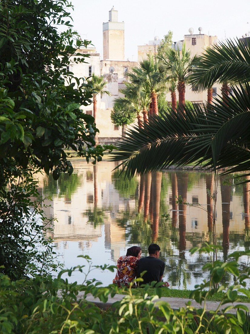 A couple enjoying the peace and the view through the palm trees at the Medina of Fez, one of the four royal cities in Morocco