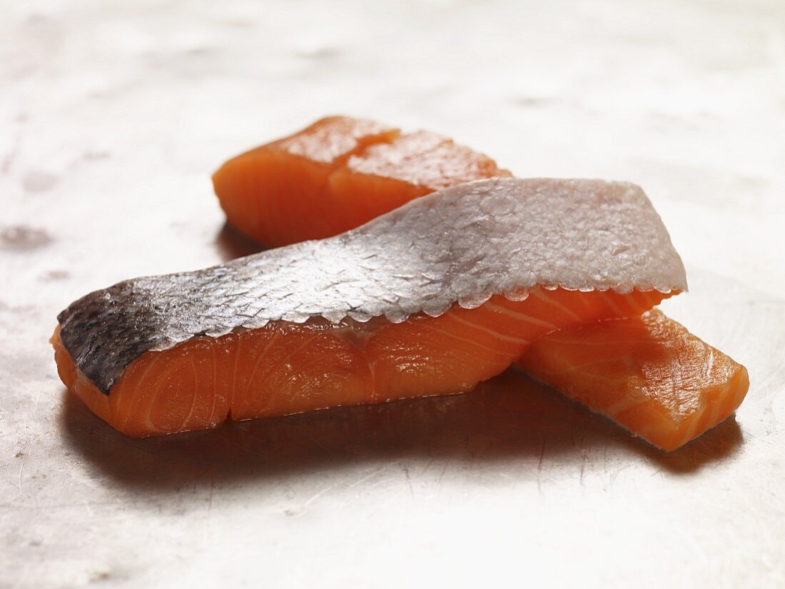 Two raw salmon fillets on metal surface