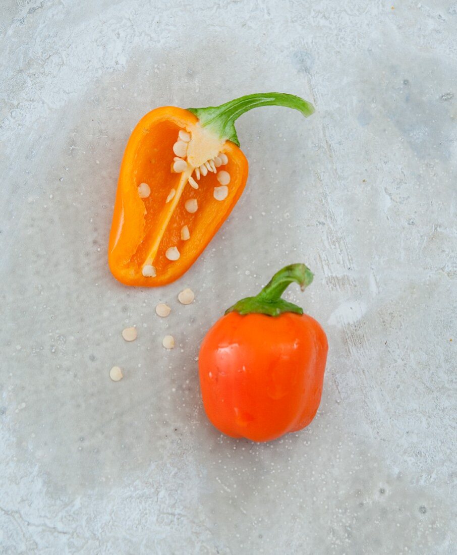 Orangefarbene Paprikaschoten, ganz und halbiert