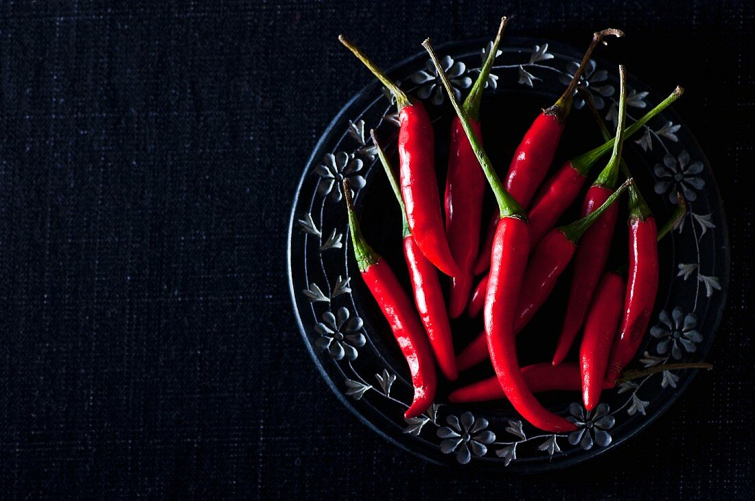 Fresh red chilli peppers on a plate (seen from above)