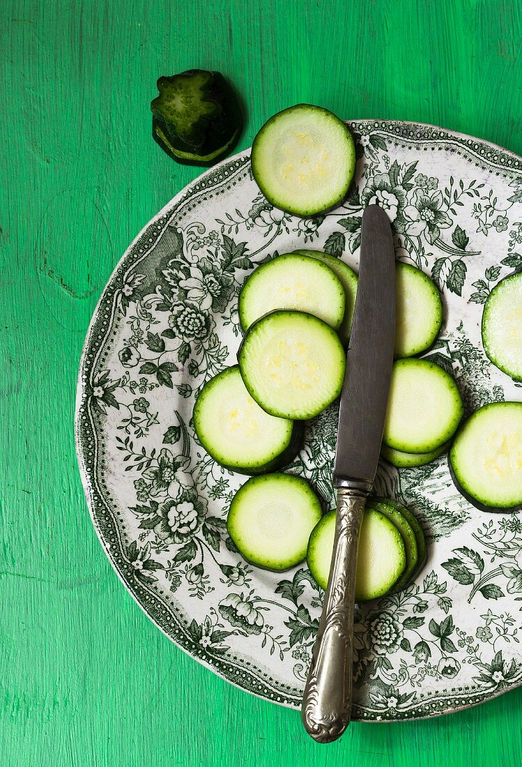 Zucchinischeiben und Messer auf Teller