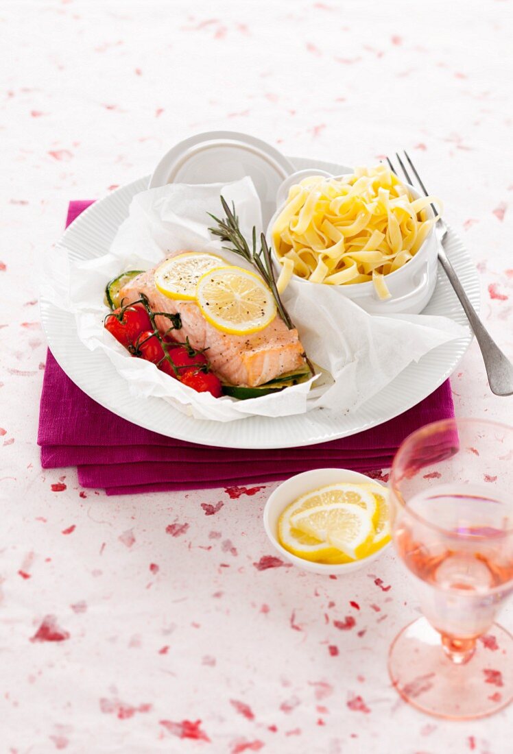 Salmon fillet in parchment paper with lemon, tomatoes and tagliatelle