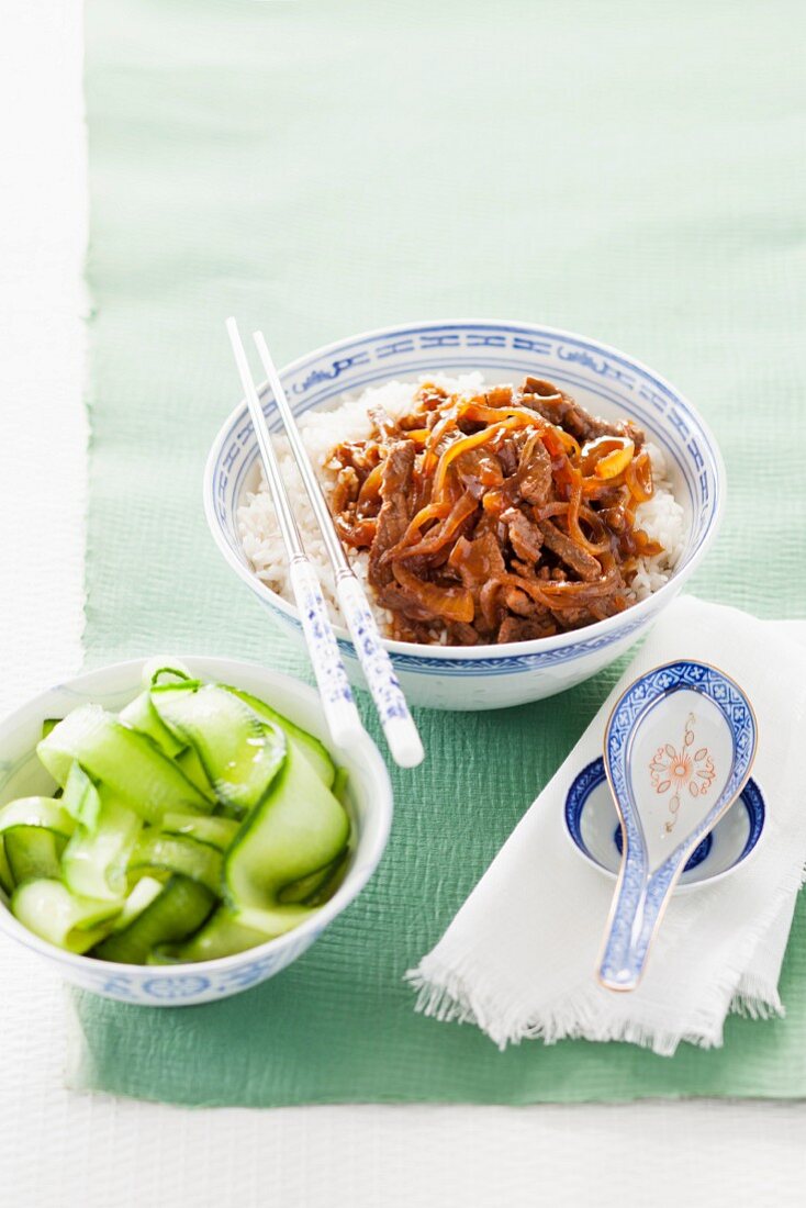 Rindfleischstreifen mit Ingwer, Sojasauce und Sake aus dem Wok mit Gurkensalat