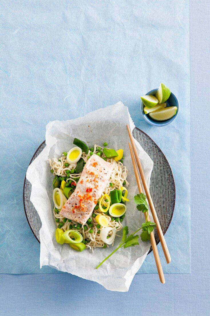 Salmon on a bed of oriental noodles with leek in parchment paper
