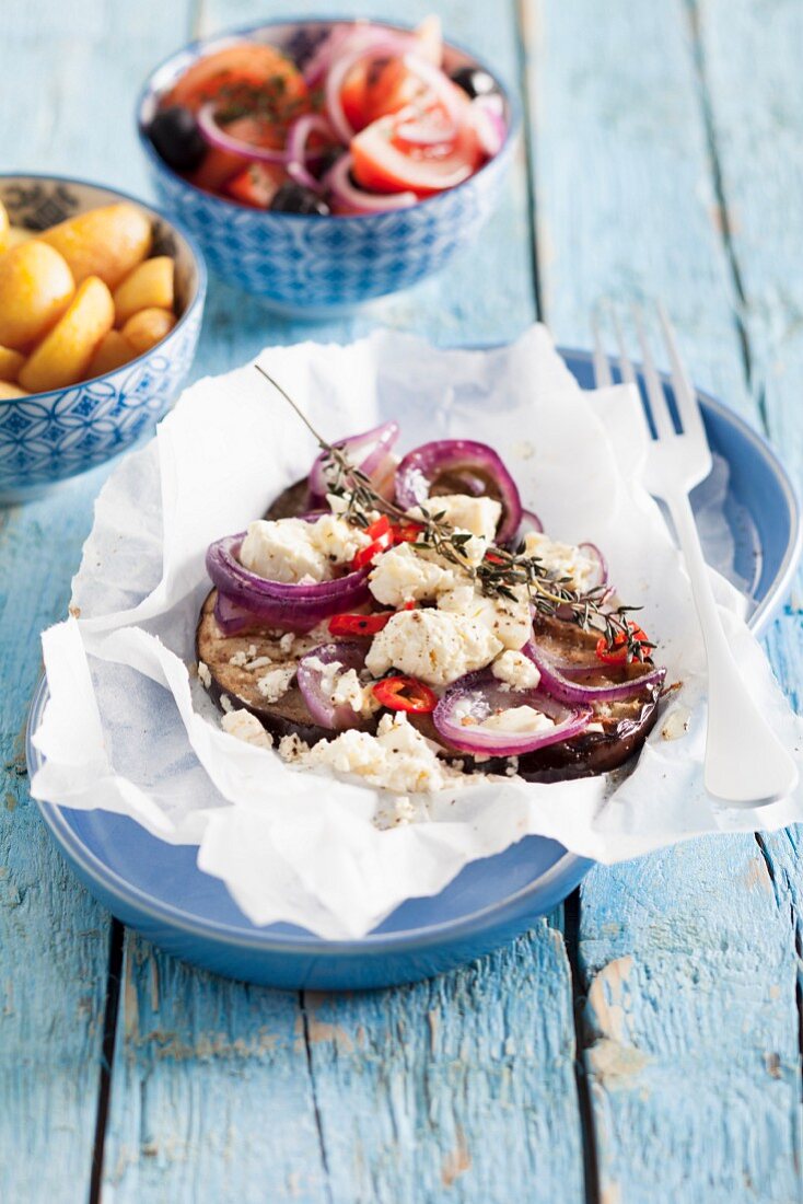 Greek aubergines with red onions and feta cheese in parchment paper