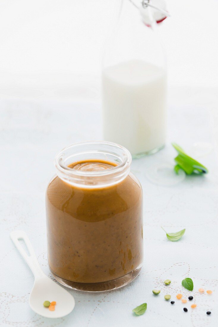 A jar of baby lentil purée with a bottle of milk in the background