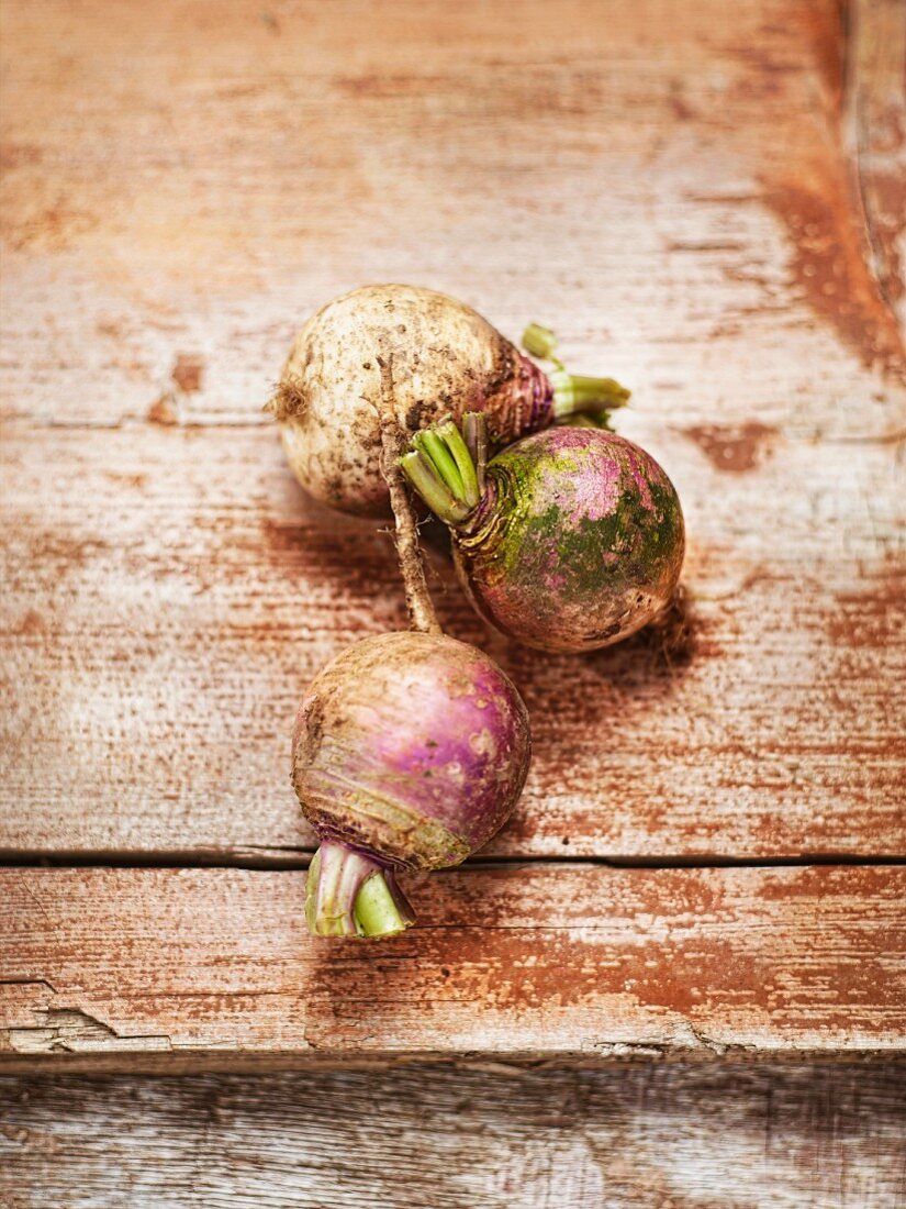 Three organic turnips on a wooden surface