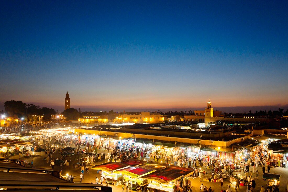 Blick über den beleuchteten Gauklermarkt Djemaa el-Fna bei Sonnenuntergang in Marrakesch, Marokko