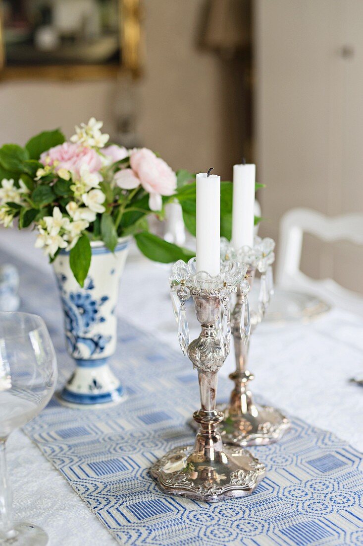Silver candlesticks and posy on white and blue patterned tablecloth