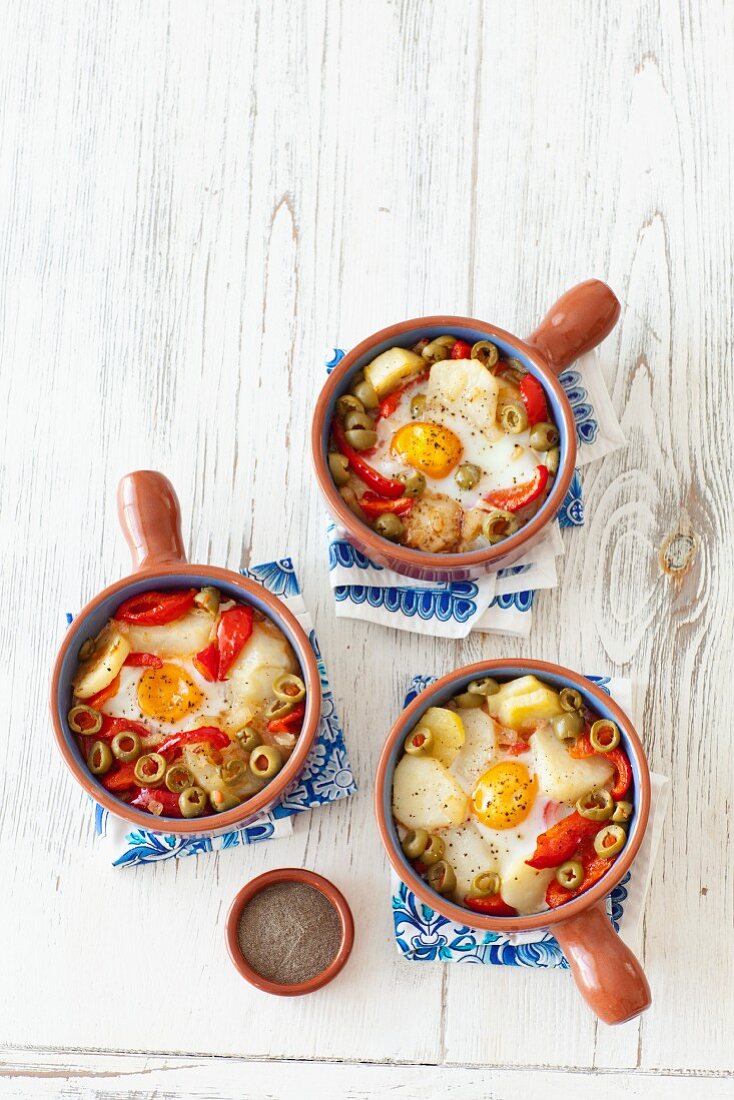 Baked eggs with potatoes, peppers, onions, olives and tomatoes