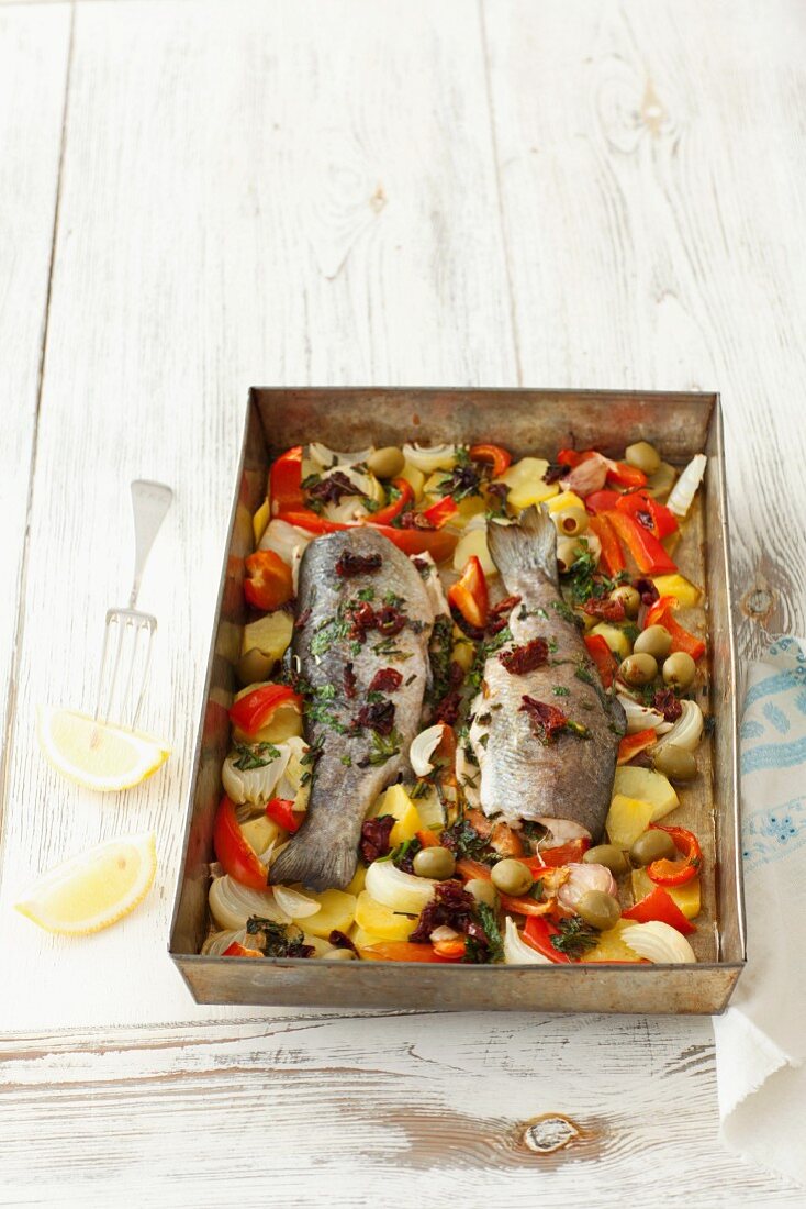 Baked trout with herbs, butter and vegetables on a baking tray