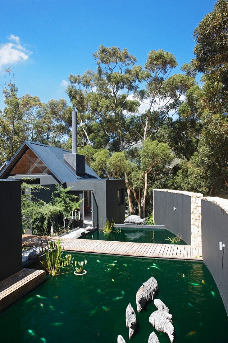 Formal ponds separated by wooden bridge leading from house to garden gate