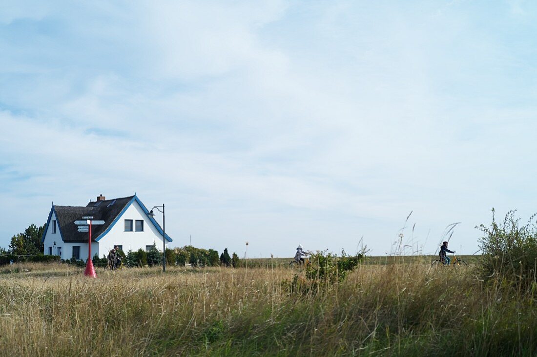 Cyclists close to a thatched roof house near Neuendorf, Hiddensee