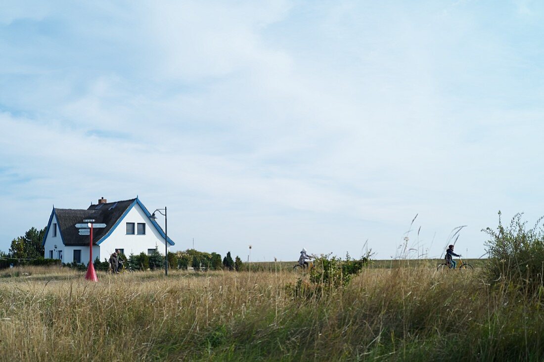 Fahrradfahrer in der Nähe eines Reetdachhauses bei Neuendorf, Hiddensee