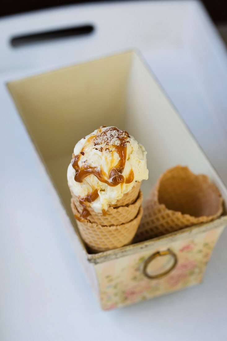 Vanilla ice cream with caramel sauce and chopped nuts in an ice cream cone