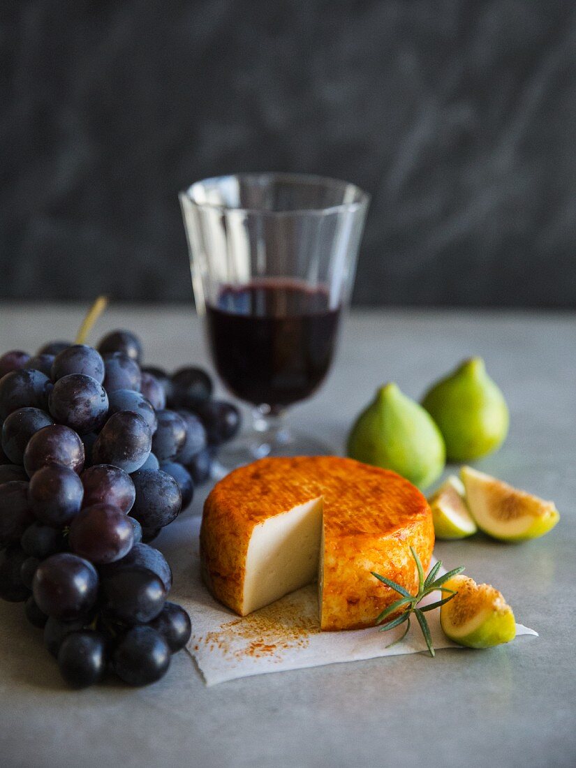 An arrangement of grapes, wine, cheese and figs