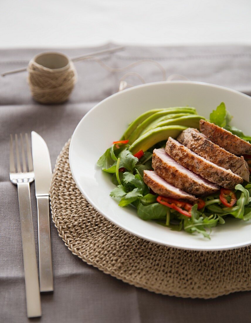 Grilled tuna on a bed of lettuce with avocado and peppers