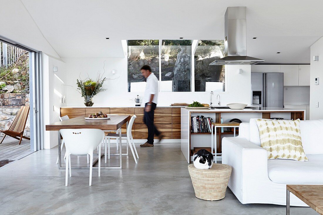 Designer kitchen with dining area in open-plan interior; white couch in foreground