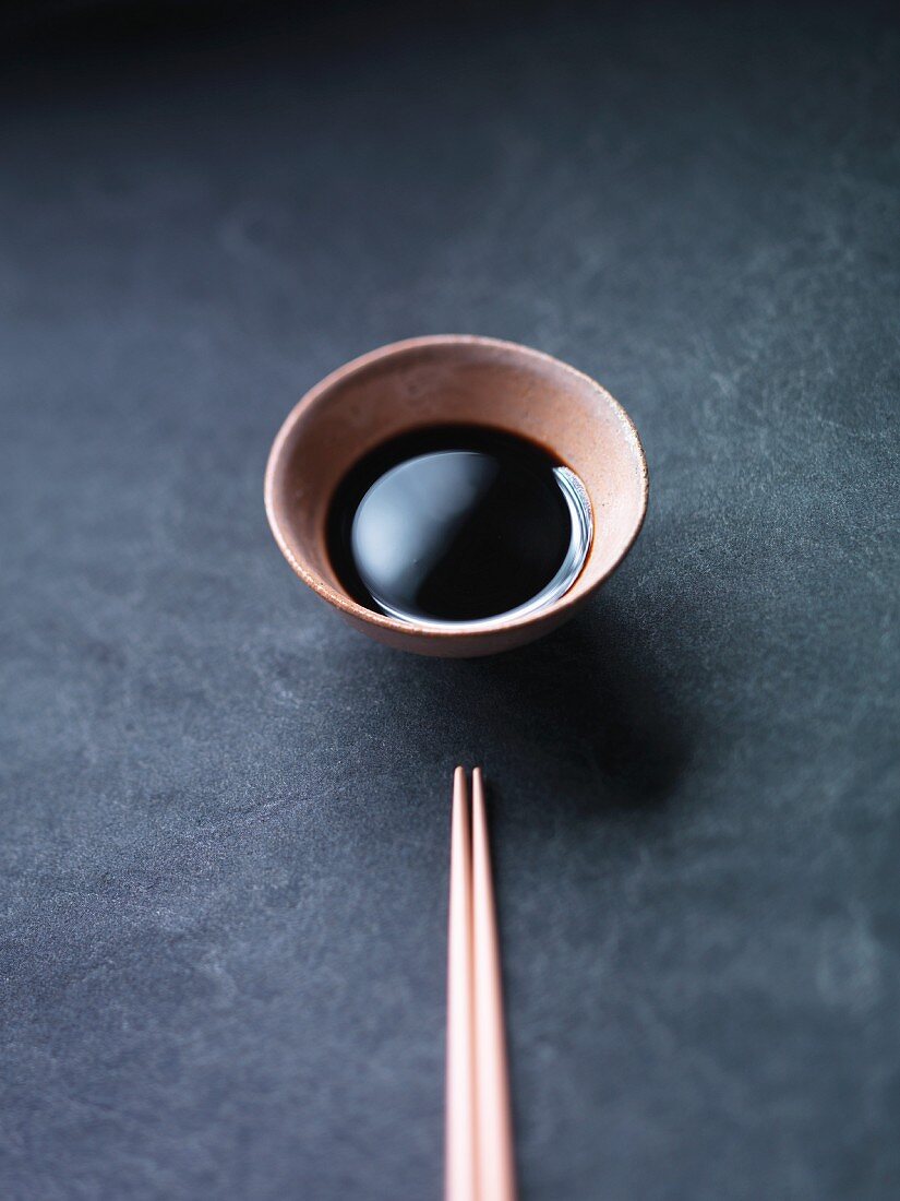 A bowl of soy sauce and chopsticks