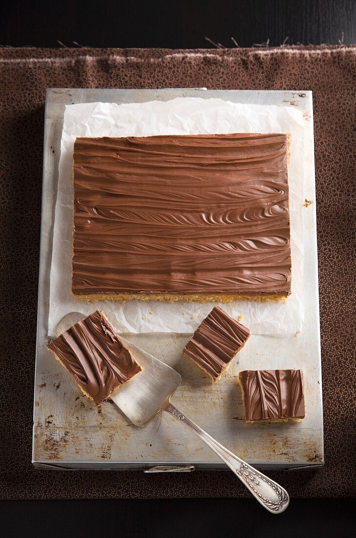 Millionaires shortbread on a baking tray with a cake slice