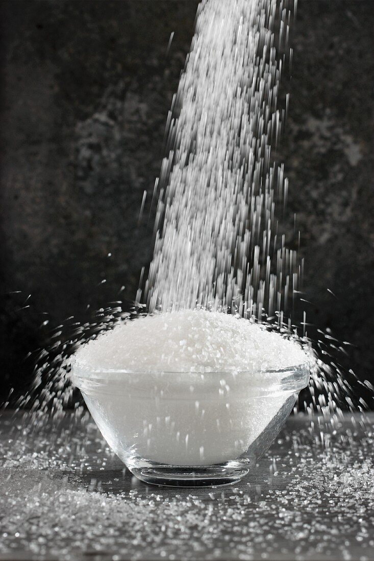 Sugar being poured into a bowl
