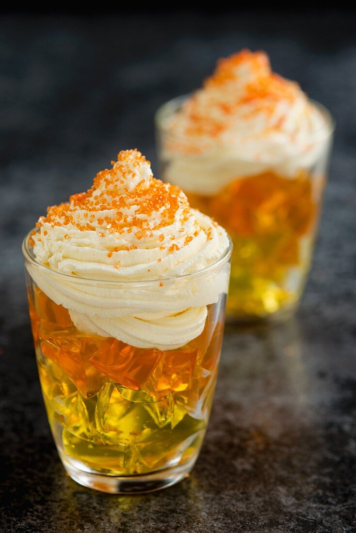Layered yellow and orange jelly topped with whipped cream and orange sugar sprinkles