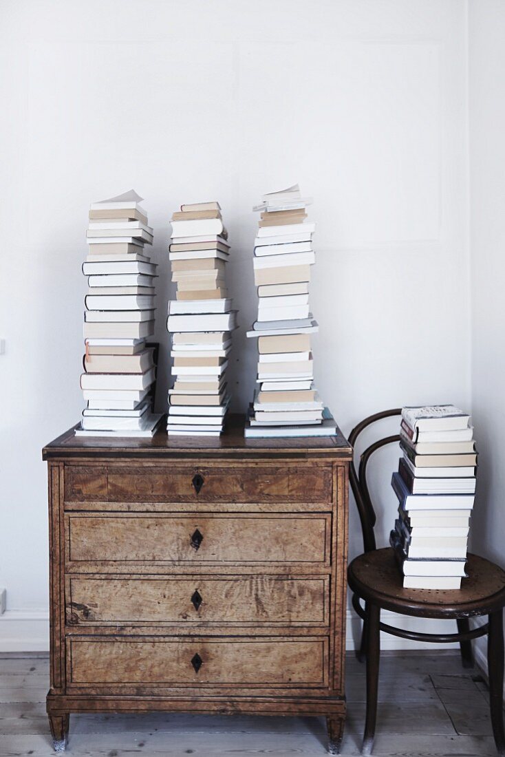 Stacked books on old chest of drawers next to Thonet chair