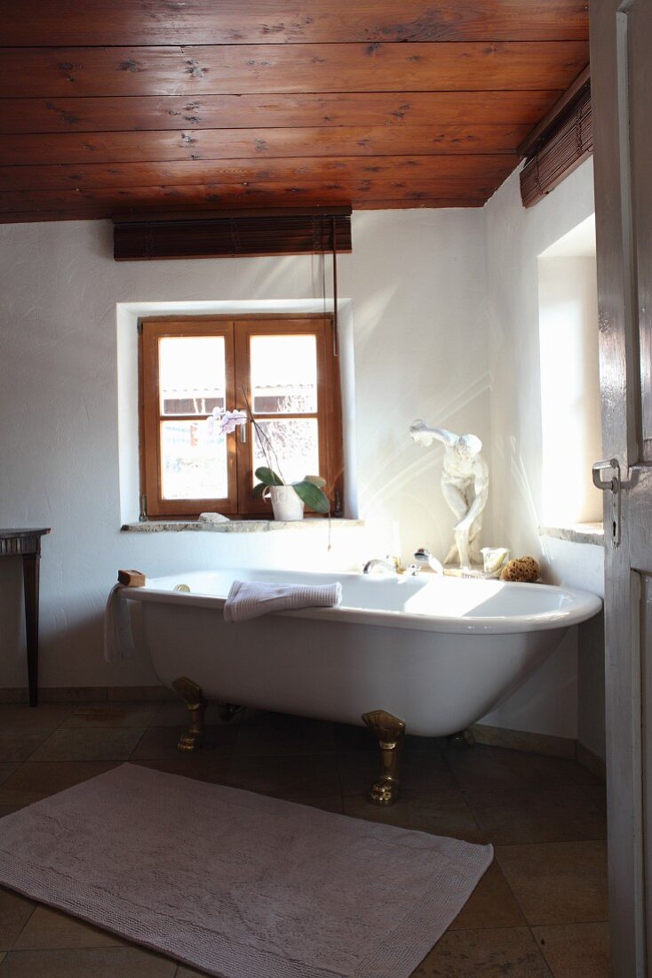 Blick durch offene Tür auf freistehende Badewanne vor Fenster in renoviertem Bad