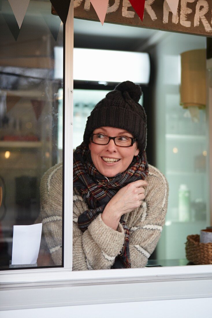 A sales assistant in a kiosk wearing knitted hat