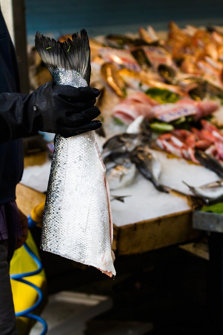 Fischhändler mit halbem Lachs auf Fischmarkt