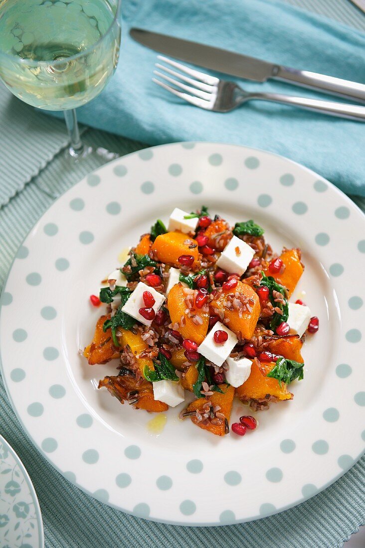 A salad with roasted vegetables, pomegranate seeds and feta cheese