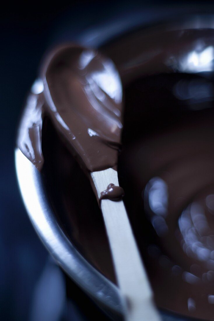Geschmolzene Schokolade in Schüssel und auf Löffel