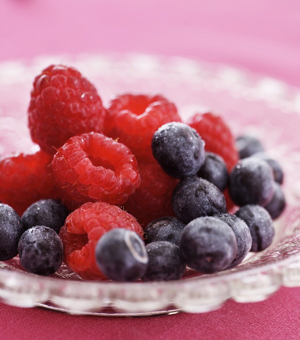 Fresh raspberries and blueberries in a glass bowl