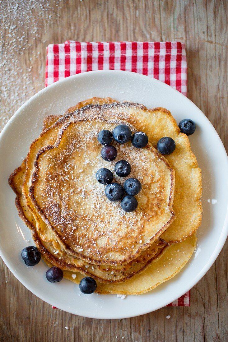 A stack of pancakes dusted with icing sugar