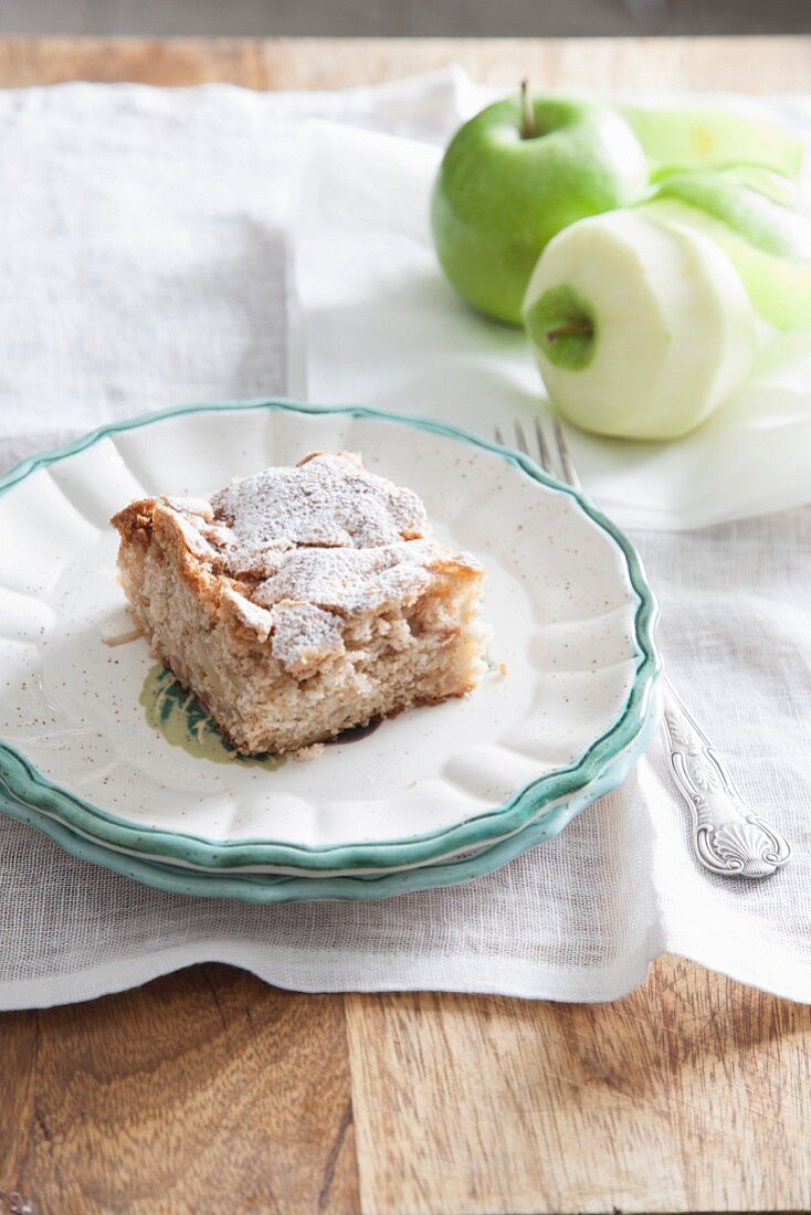 A slice of apple crumble cake with icing sugar