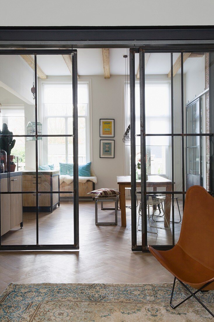 View through glass and steel sliding doors into open-plan kitchen with dining area